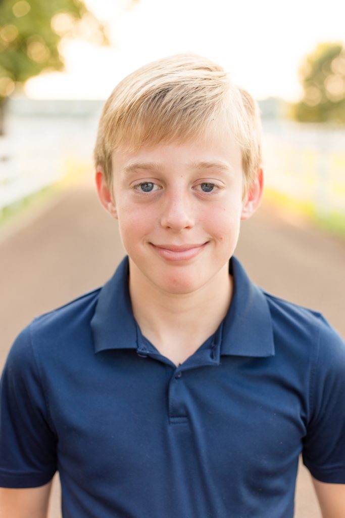 Boy in navy shirt stands in front of Harlinsdale Farm in Franklin, TN with family photography team Wisp + Willow Photography Co. Click to see more from this session on our blog!