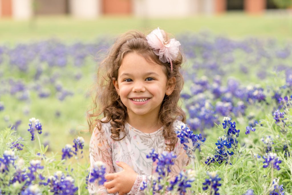 Girl sits in bluebonnet field with Plano family photographer Wisp + Willow Photography Co. 