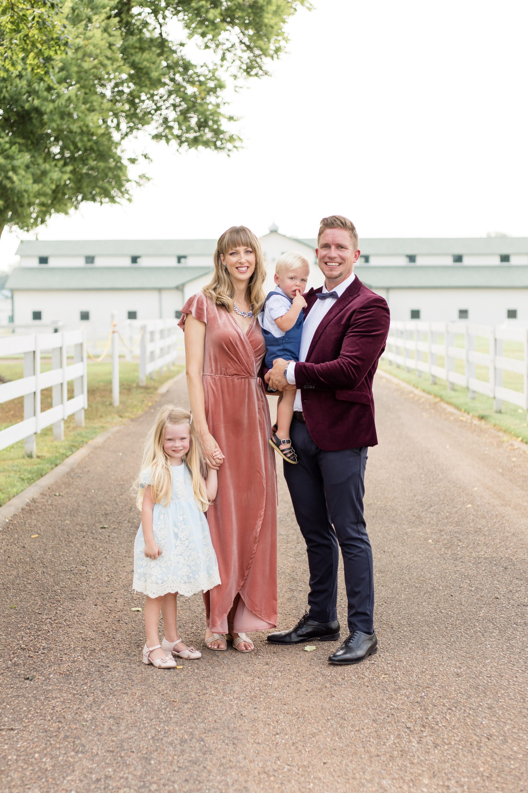 Beautiful family of 4 poses in front of white barn at Harlinsdale Farm during family portrait session in the fall with Wisp + Willow Photography Co. Click to learn more about why we love Harlinsdale Farm! 