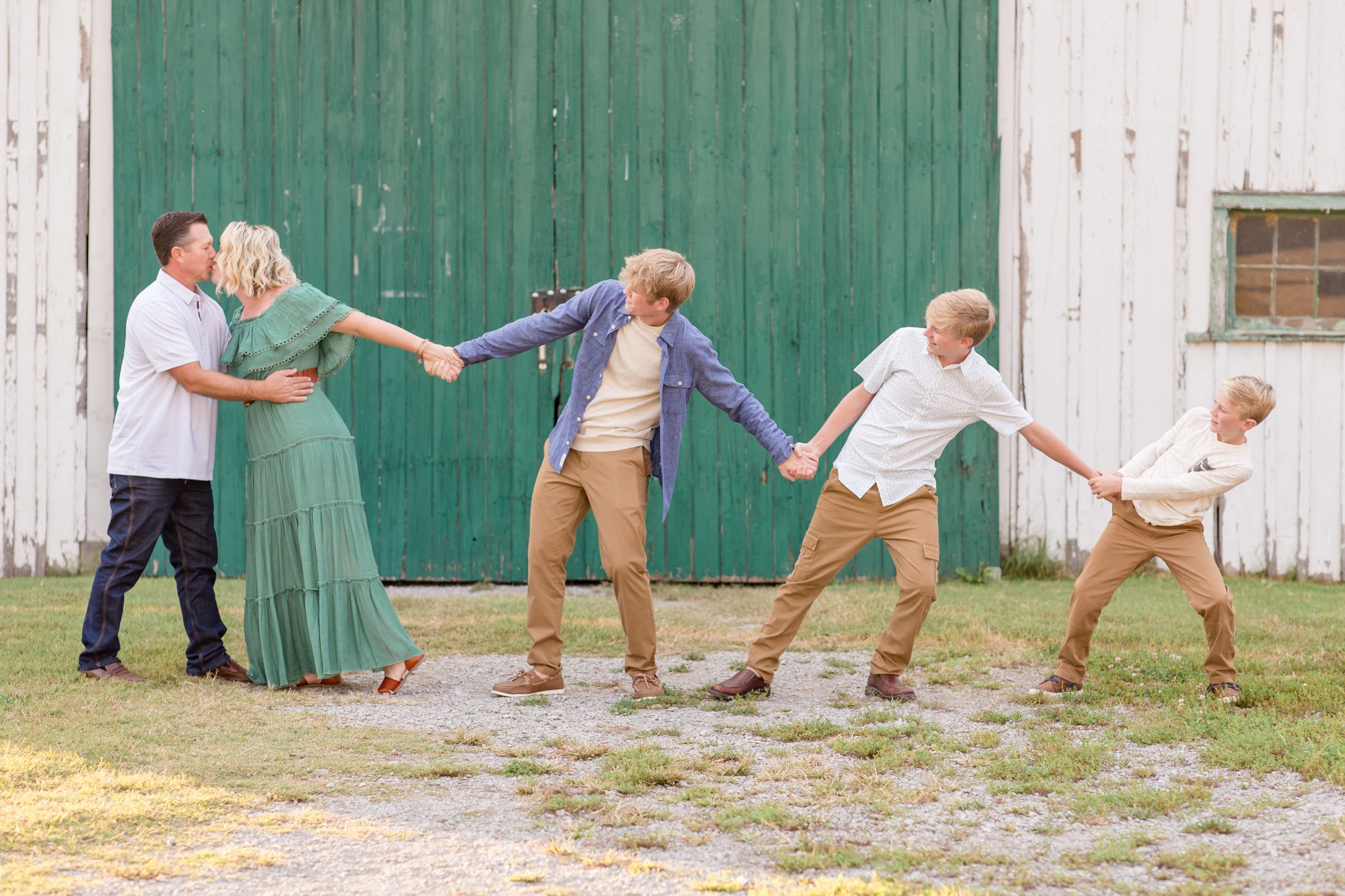 Mom and dad kiss while kids try to pull mom away during family portrait session with family photography team Wisp + Willow Photography Co. Click to see more about why we love this session location in Nashville, TN!