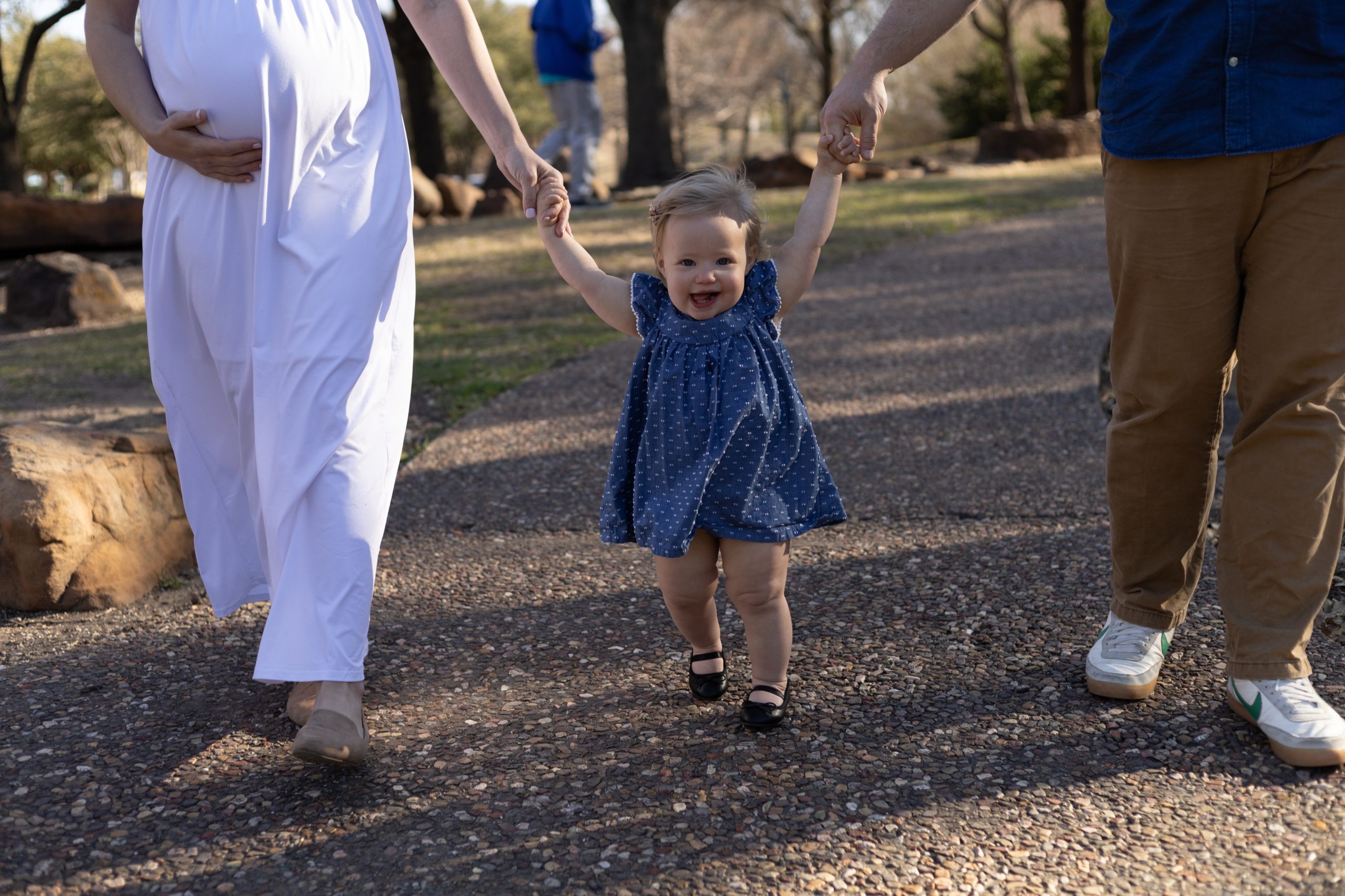 Mom and dad walk with young daughter in blue dress during maternity session with Wisp + Willow Photography Co. Click to see more from this session live on the blog now! 