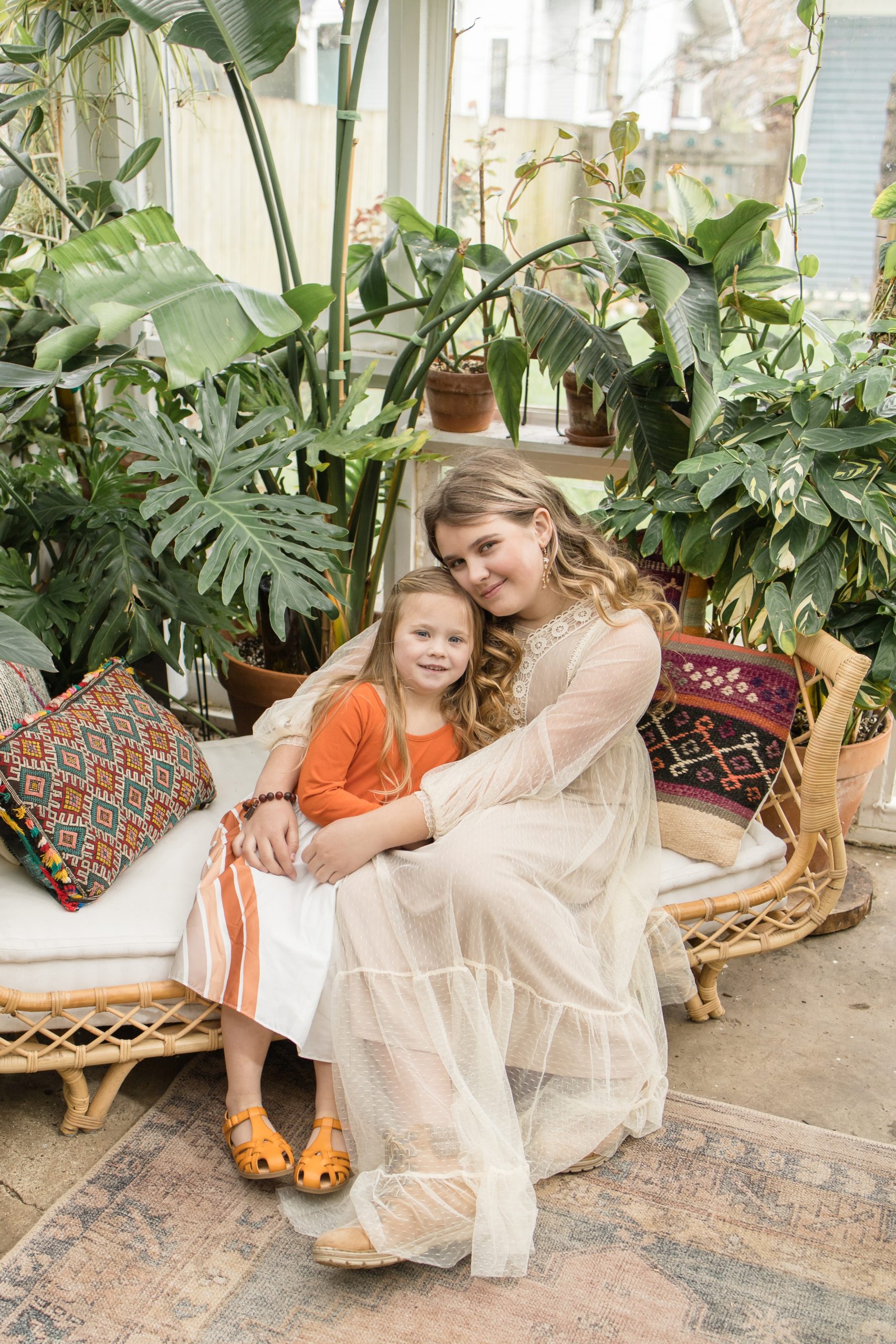 Sisters hug each other on bench in East Nash Greenhouse in Nashville, TN during spring mini sessions with Wisp + Willow Photography Co. Click to see more from these minis live on the blog now! 