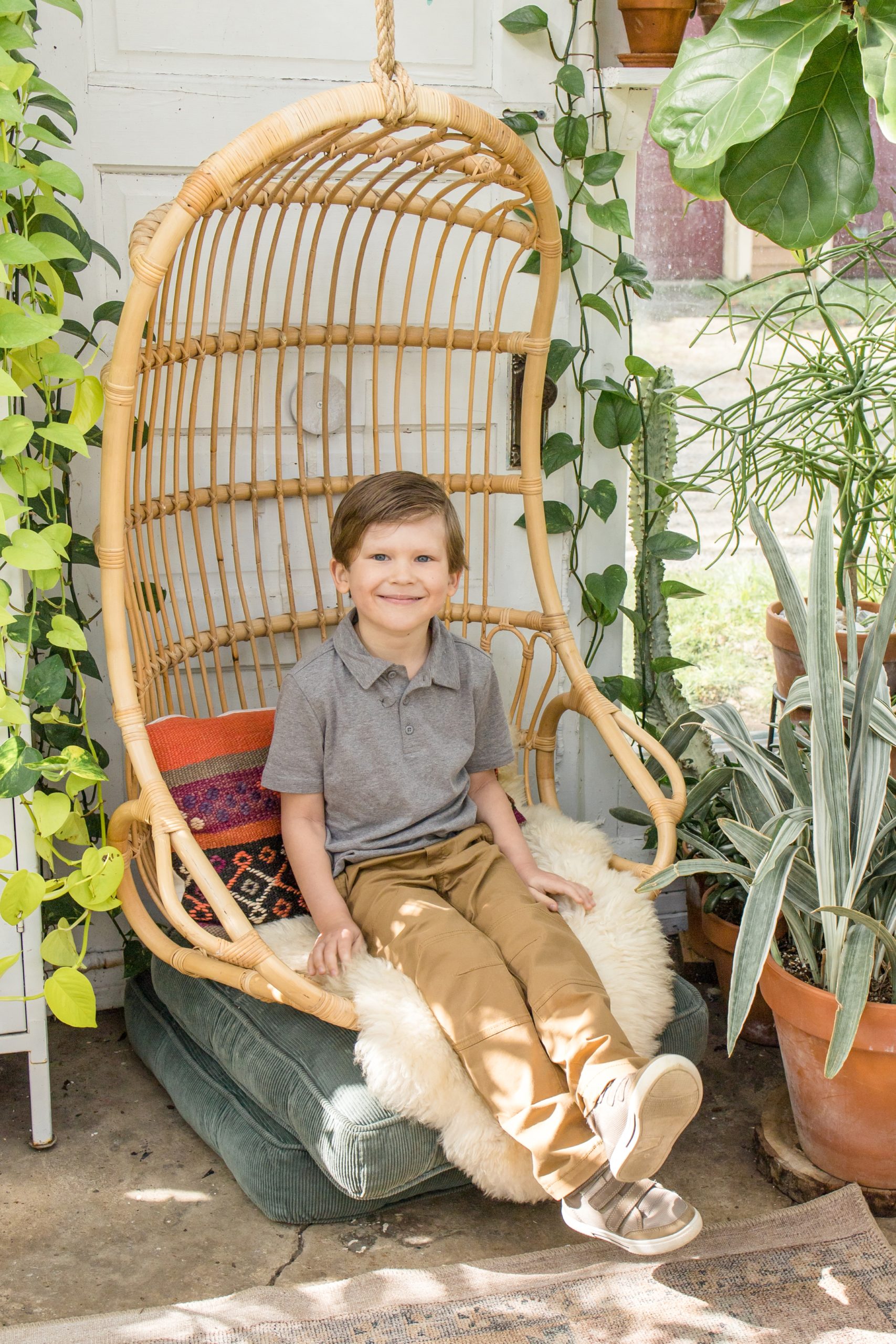 Boy in grey button up sits in chair at East Nash Greenhouse during spring minis with family photography team Wisp + Willow Photography Co. Click to see more from this set of minis live on the blog now! 