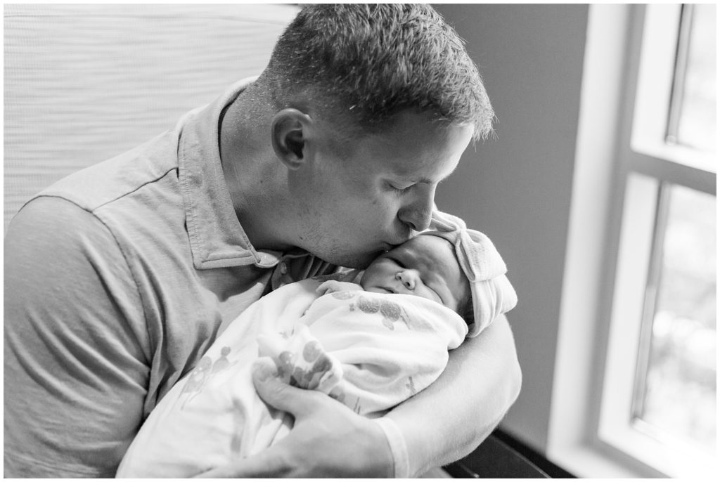 Dad is kissing his sweet baby girl in this beautiful black and white shot.