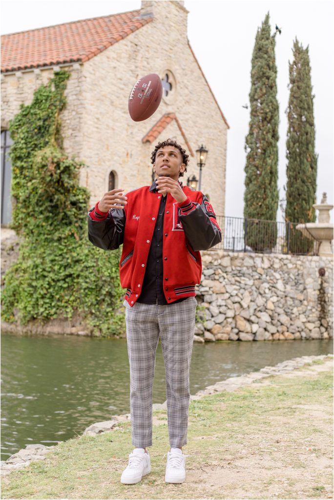 At this client senior session he tossed around his football. He also wore his black and red letterman jacket. Client is standing in front of a beautiful stone building and rock wall. 