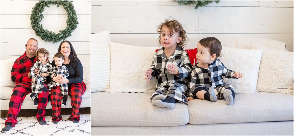 Sweet family of 4 are seated on a white couch. Dad is wearing a black and red buffalo plaid long sleeve pajama set. Mom is wearing a long sleeve black shirt and red and black buffalo plaid pants. Brothers are wearing matching black and white long sleeve pajamas. 