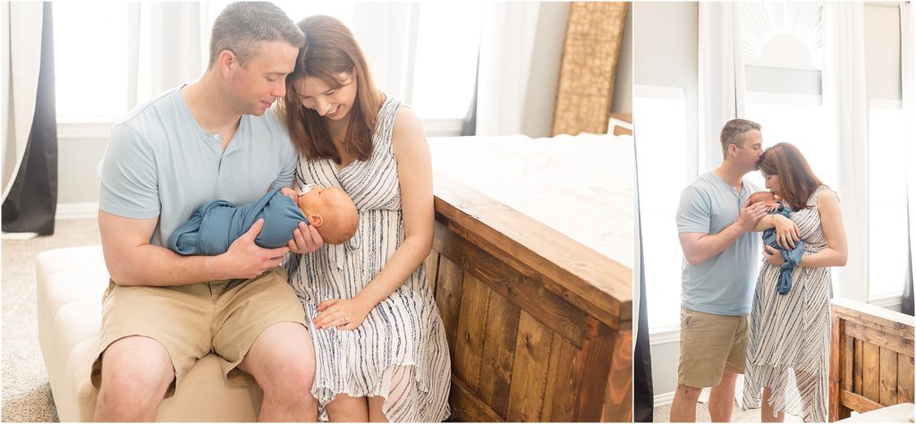 Cute family of 3 in the bedroom. Mom is wearing a sleeveless gauze-striped dress. Dad is wearing a light blue shirt and khaki shorts. The baby boy is swaddled in blue.