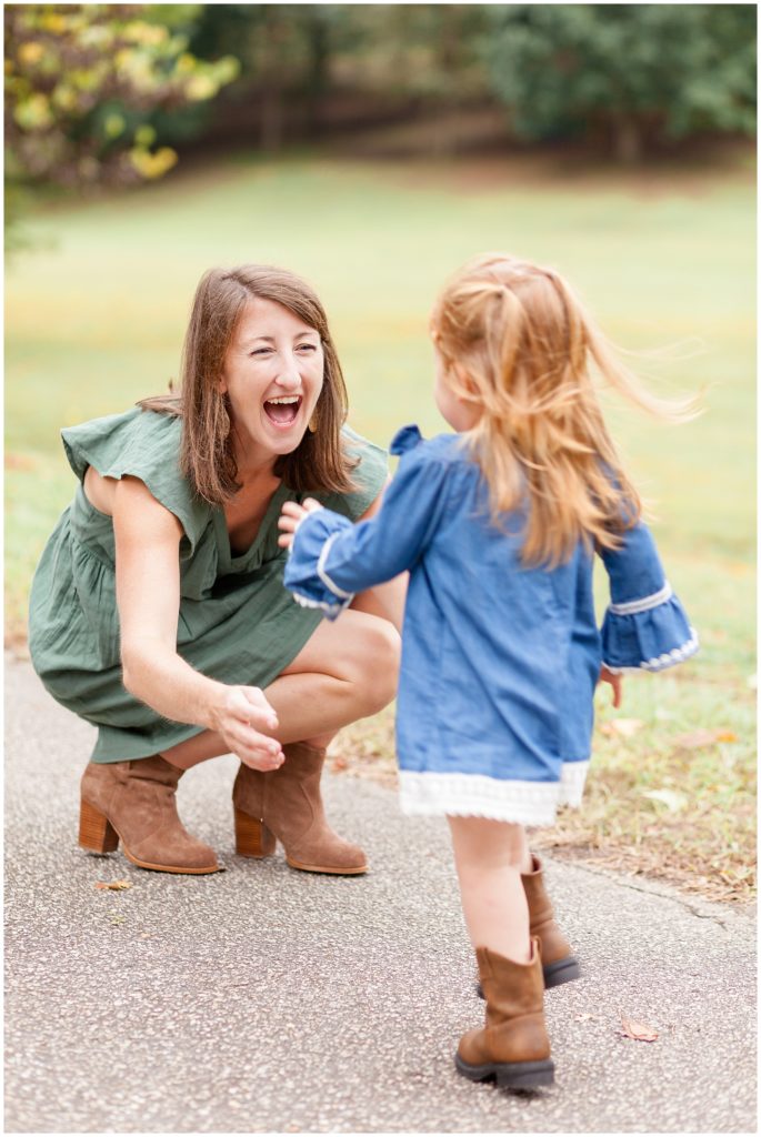 Mom in green dress laughs while daughter in blue dress runs into her arms during fall family session with Wisp + Willow Photography Co. 