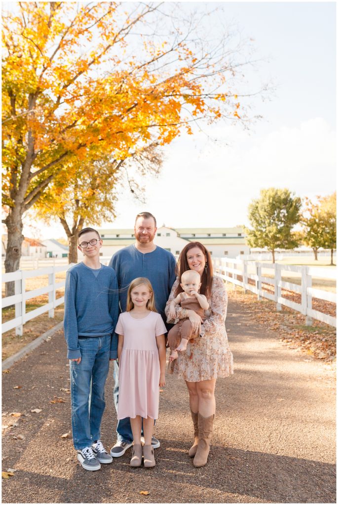 Family of 5 pose in front of Harlinsdale Farm in Franklin, TN with white picket fence during fall family photo session. 