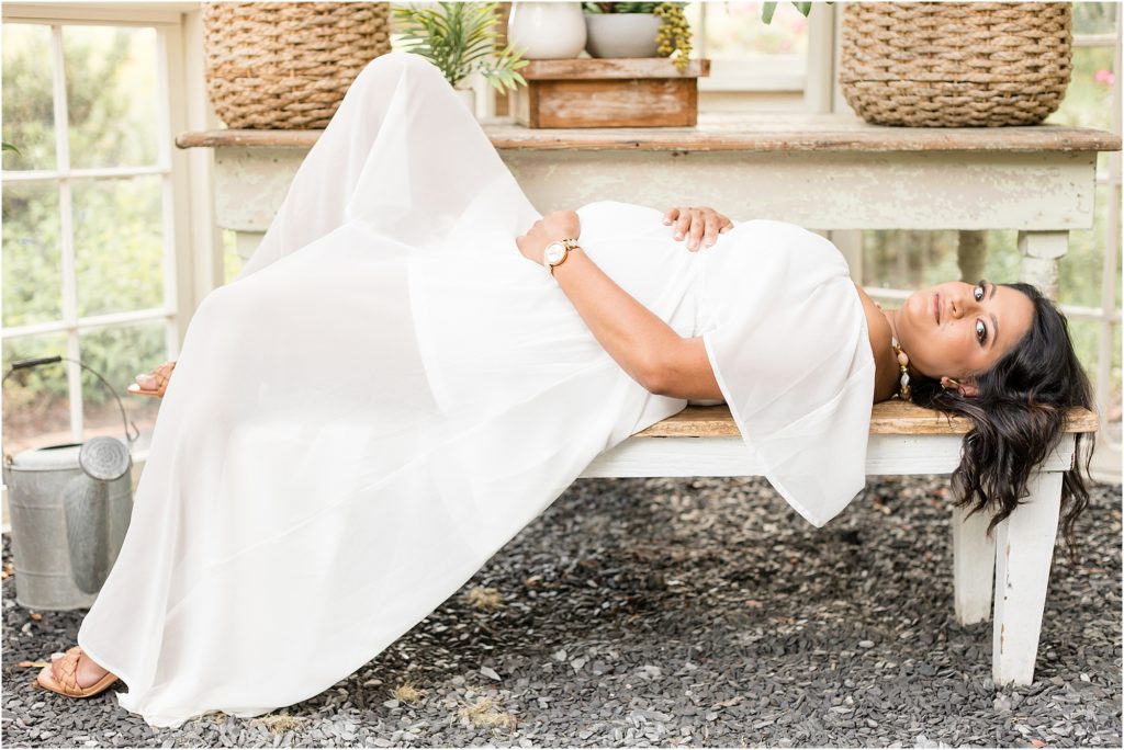 This gorgeous mom-to-be is pictured here in this beautiful greenhouse. She is wearing such a pretty off-the-shoulder long white dress.