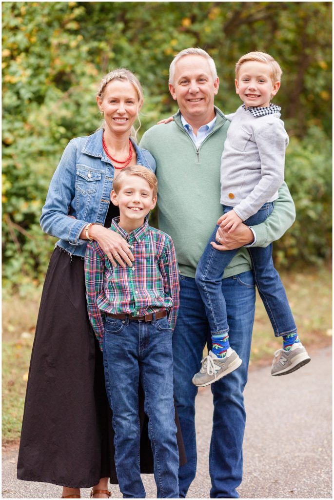 Mom and Dad and 2 sons stand together outside and smile during fall family session in Raleigh, NC with Wisp + Willow Photography Co.