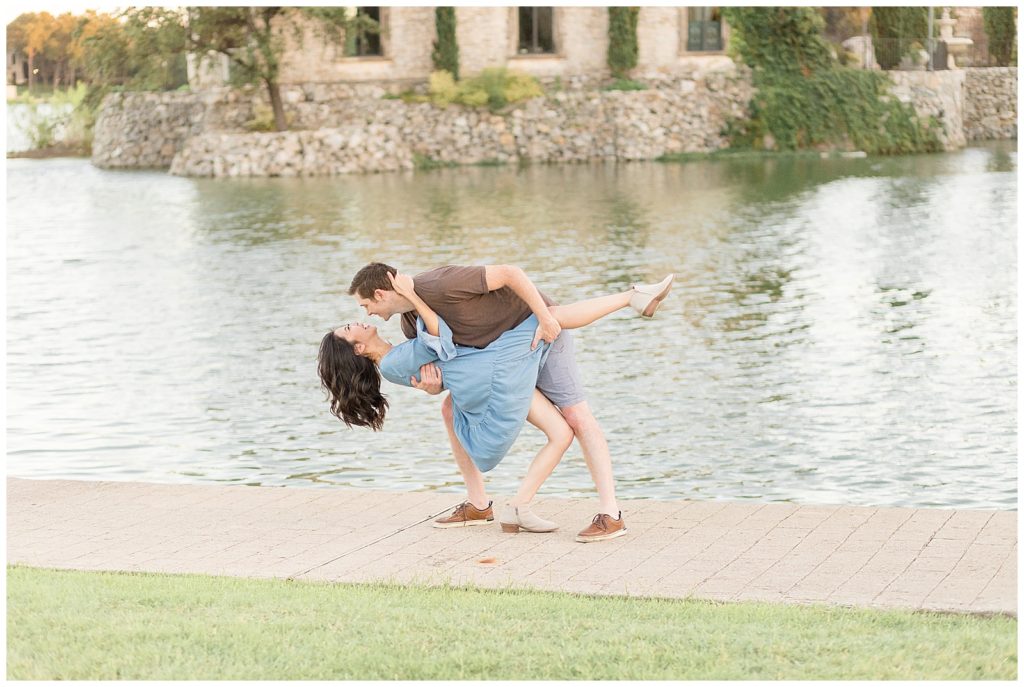 Husband dips wife as she laughs in front of Adriatica Village water in McKinney, TX for their Wisp + Willow Photography Co. family photographer.