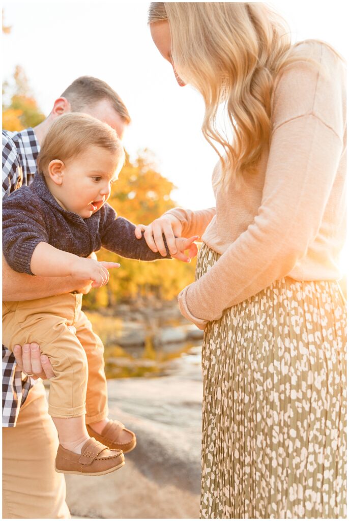 Little boy points to his mom's belly to show his excitement for the baby on the way during their Belle Isle family portraits.