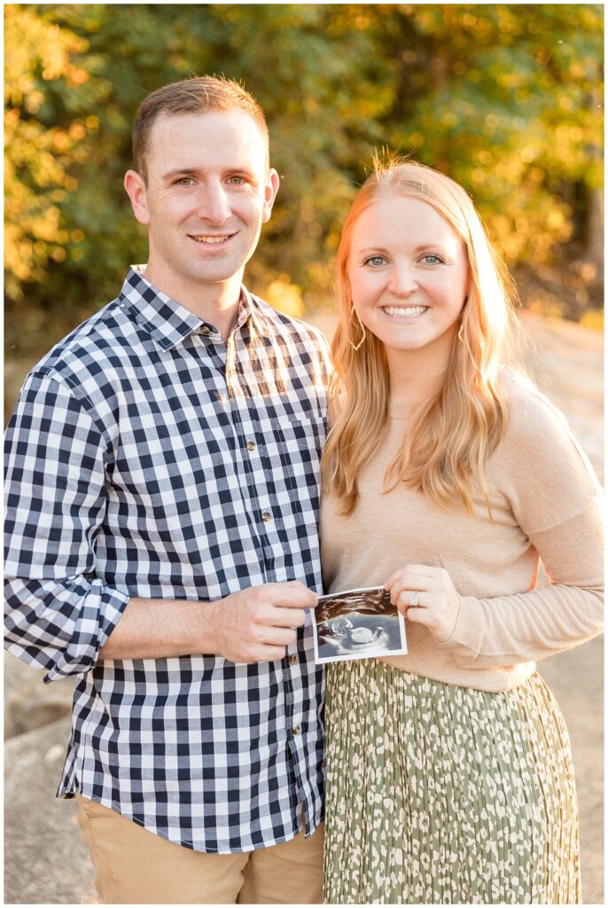 Mom and Dad smile at camera with sonogram to share their baby announcement during their Richmond family photography session with Wisp + Willow Photography Co.