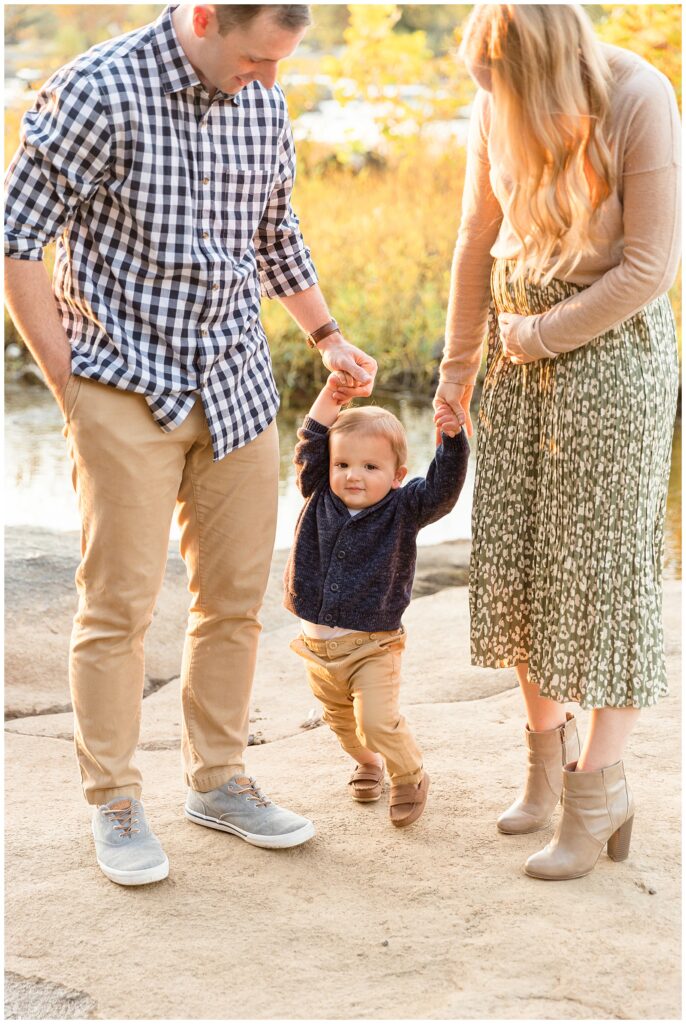 Richmond family photographer, Wisp + Willow Photography Co. capture toddler holding hands with Mom and Dad as mom holds belly to share baby announcement.