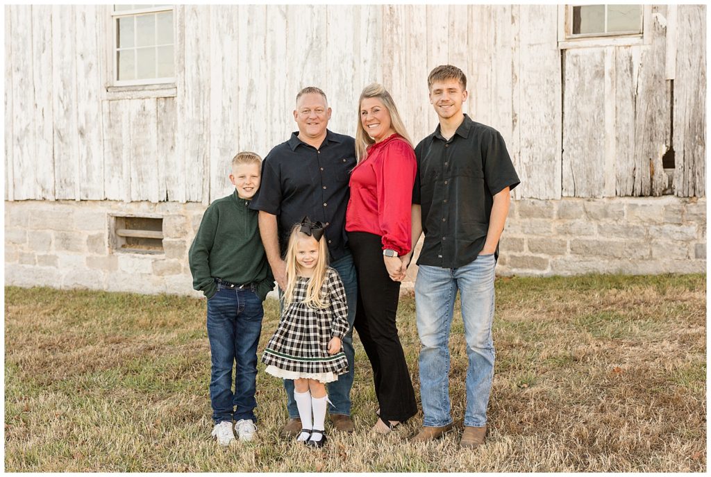 Family of 5 smiles for family portraits i Nashville, TN wearing coordinating outfits in black, red, white, and green colors.  Head to the Wisp + Willow Photography Co. blog to see more!