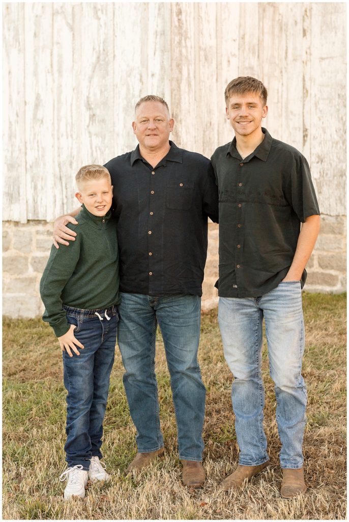 Dad stands with two sons wearing black and green shirts and jeans for their photography session in Nashville, TN.