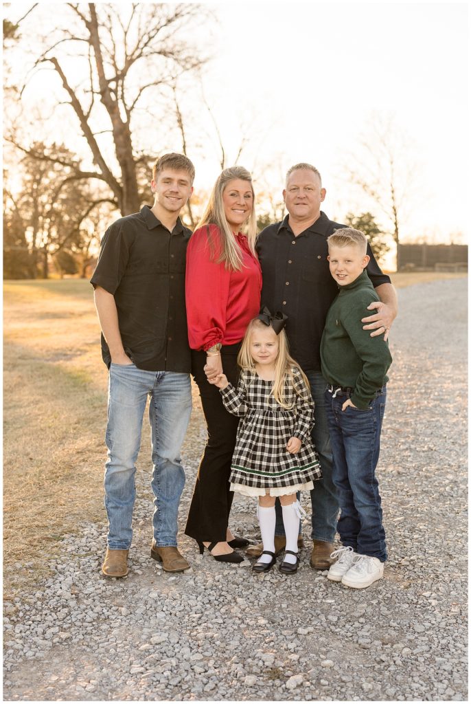Family wears coordinating outfits for family photography session in Nashville, TN.  Mom wears a pop of red, son wears a green shirt, and dad, teen son, and daughter wear a mix of black, white, and jeans.