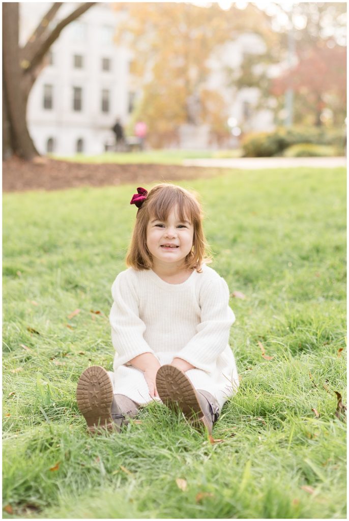 Wisp + Willow Photography Co. capture little girl sitting in the grass in downtown Raleigh, NC during her family photography mini session.