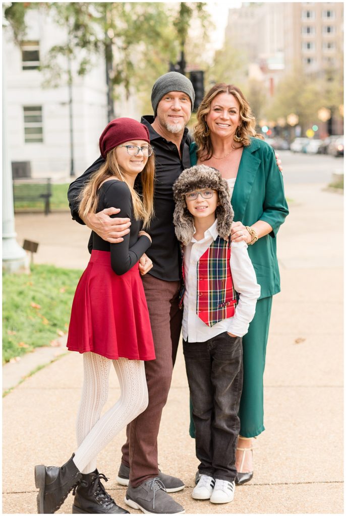 Family of 4 smiles for Wisp + Willow Photography Co. for their Christmas card picture.  They coordinate outfits wearing green, red, black, and white colors.