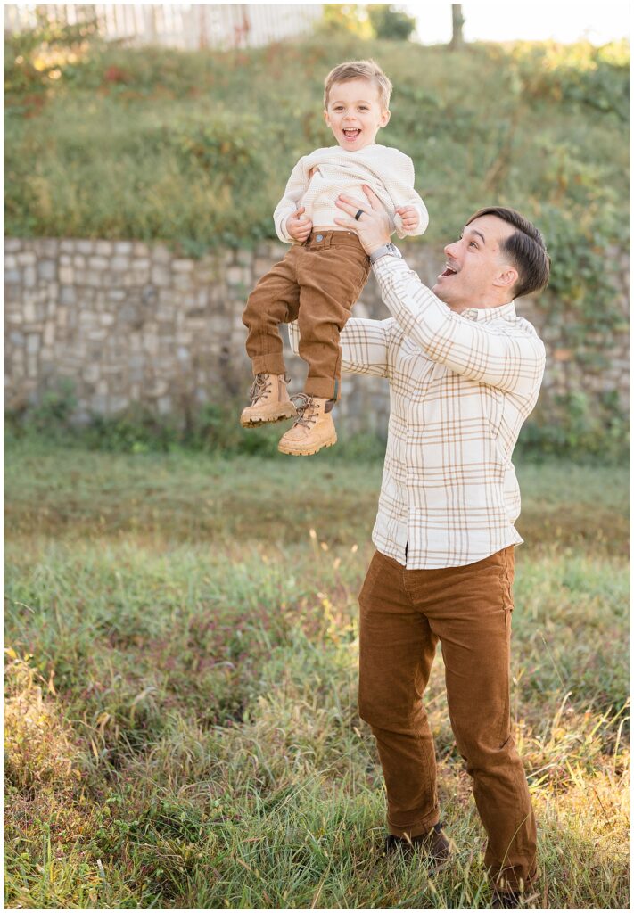 Richmond, Virginia family photographer captures Dad throwing son up in the air during their fall family photography session at Libby Hill Park.