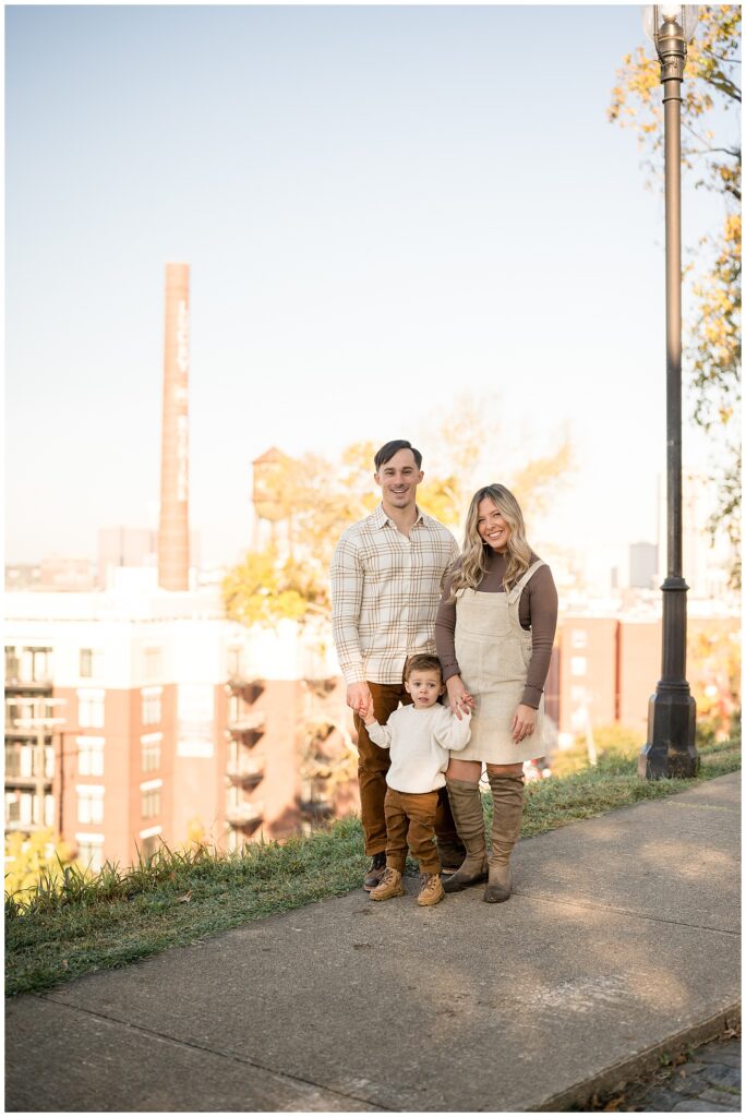 Family of 3 stand in front of iconic, Libby Hill landmark in Richmond, Virginia wearing a color combination of browns for their fall family photography session.