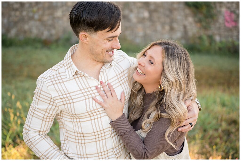 Couple look at each other sharing a moment of laughter at Libby Hill Park in Richmond, VA wearing coordinating brown outfits for their family session.