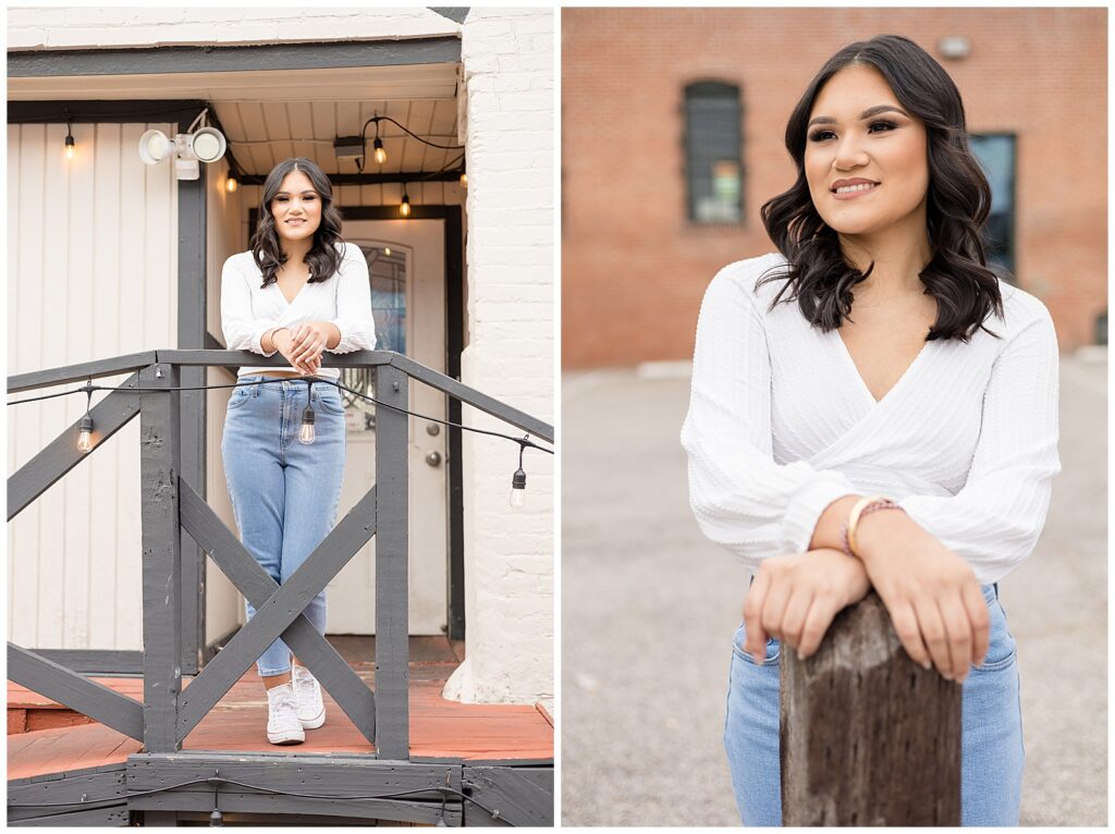Girl wears v-neck, crop top with blue jeans in front of brick and farmhouse, rustic building in downtown McKinney, TX for her senior session with Wisp + Willow Photography Co.