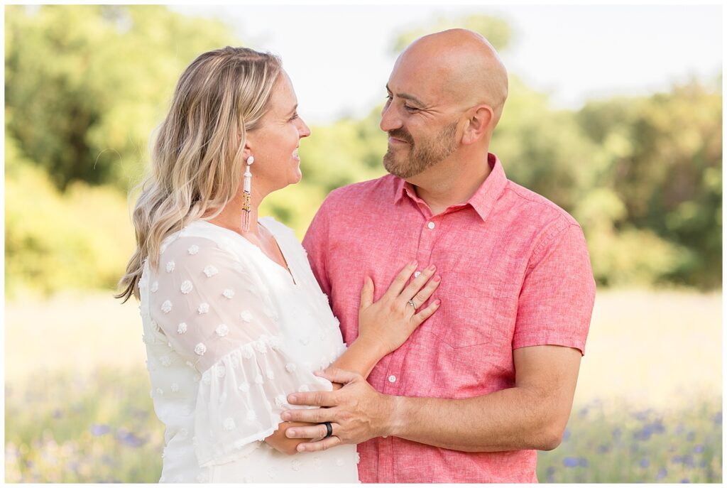 Couple smiles at each other in field during family photography session with Wisp + Willow photography sessions.