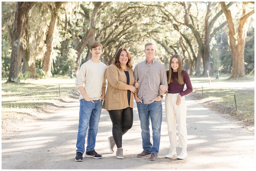 Savannah family photographer captures parents and teen son and daughter during their fall mini session at Wormsloe.  They wear neutral fall colors consisting of tan, denim, cream, and burgundy.