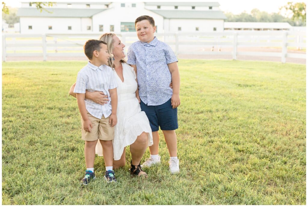 Mom kneels on one knee as she hugs boys and looks at the during their Franklin family session in TN with Wisp + Willow Photography Co.