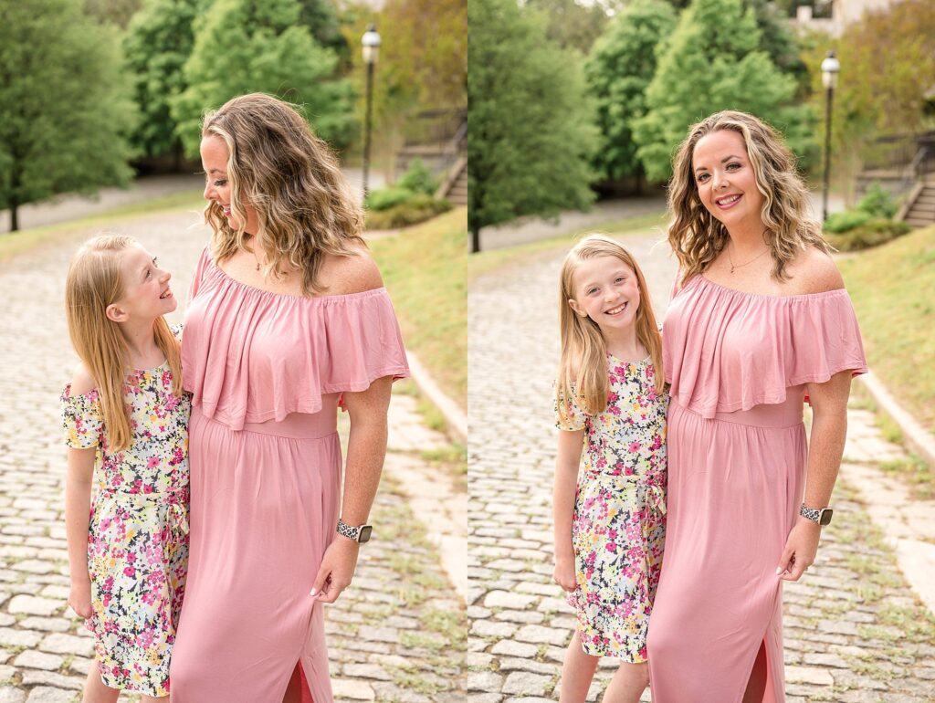 Mom wears a peach, flowy, off the shoulder dress while daughter wears a floral, spring dress during their family photography session at Libby Hill Park in Richmond, VA.  They take two pictures together- one looking at the camera and the other looking at each other.