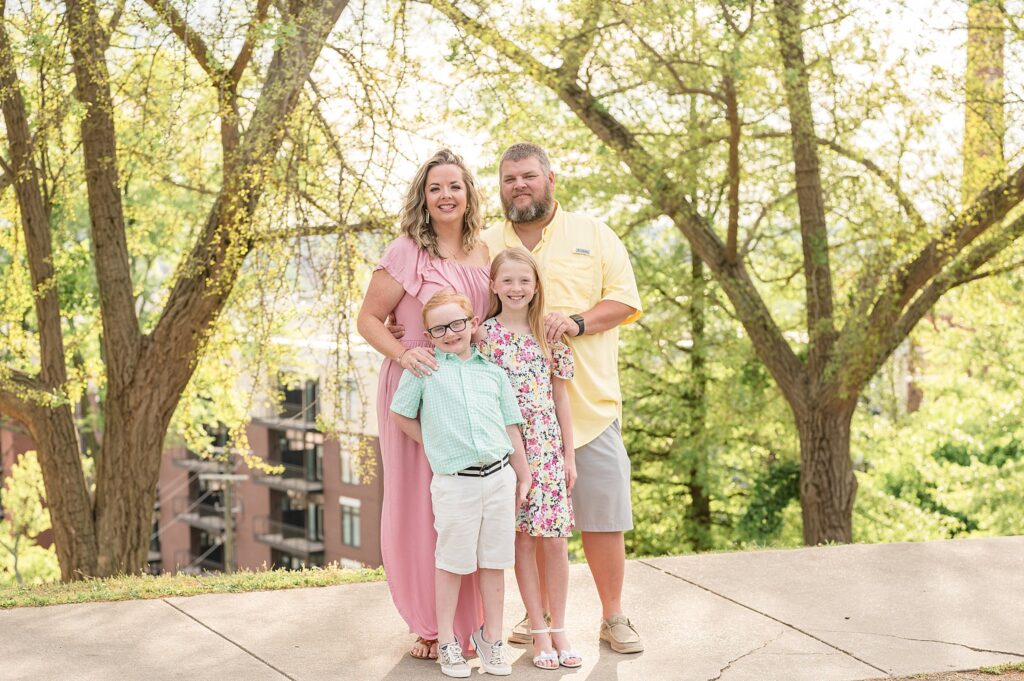 Mom and Dad with two kids-son and daughter- wear spring colors to coordinate their outfits in yellow, mint, pink, and a floral dress during their Richmond family session at Libby Hill park.