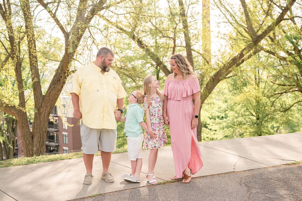 Family of 3 holds hands and looks at each other and smiles during a candid moment in their family photography session with Wisp + Willow Photography Co.  Click to see more on the blog now!