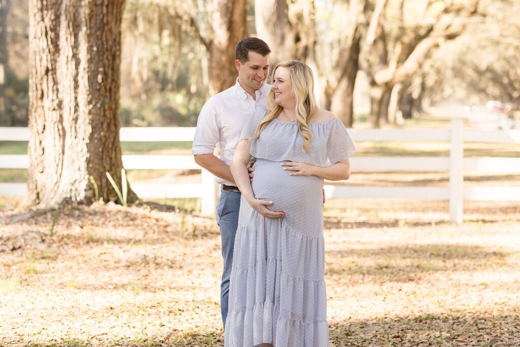 Happy couple smile as they look forward to welcoming their baby boy very soon during their Savannah maternity session with Wisp + Willow Photography Co.