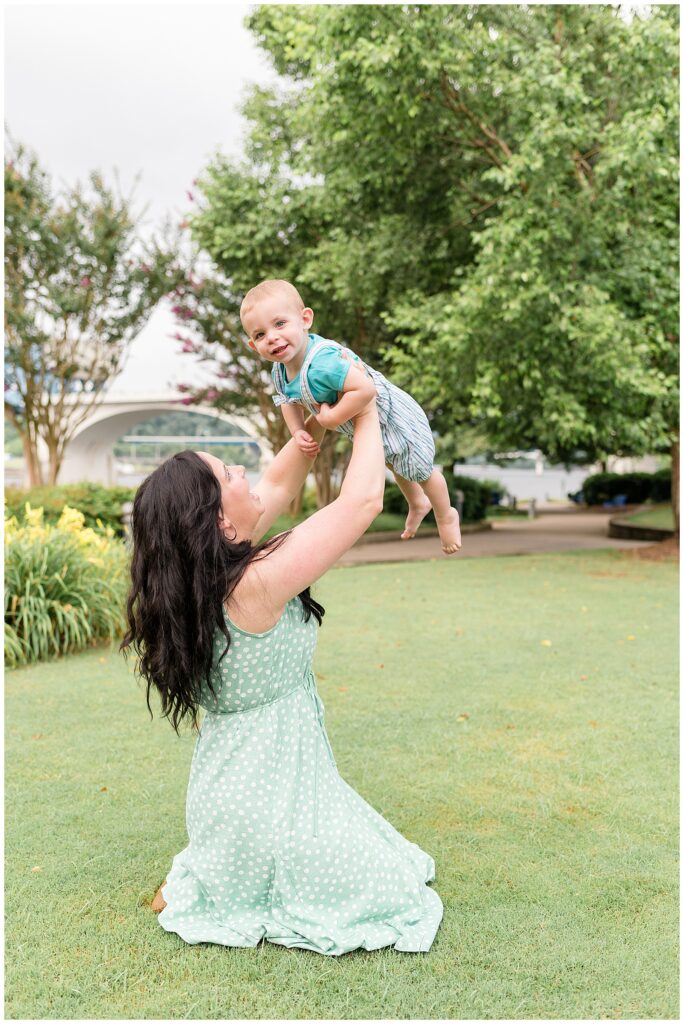 Chattanooga family photographer captures moment with mother and son as she holds son up in the air as he smiles at the camera.