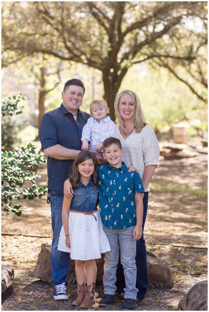Family of 5 wear coordinating outfits of blue and white for their Frisco family session at Central Park in TX.