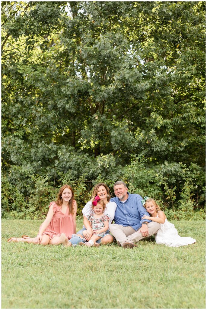 Family of 5 sit in the grass at Pinkerton Park in Franklin, TN where photographer, Wisp + Willow Photography Co. capture their Franklin family portraits.