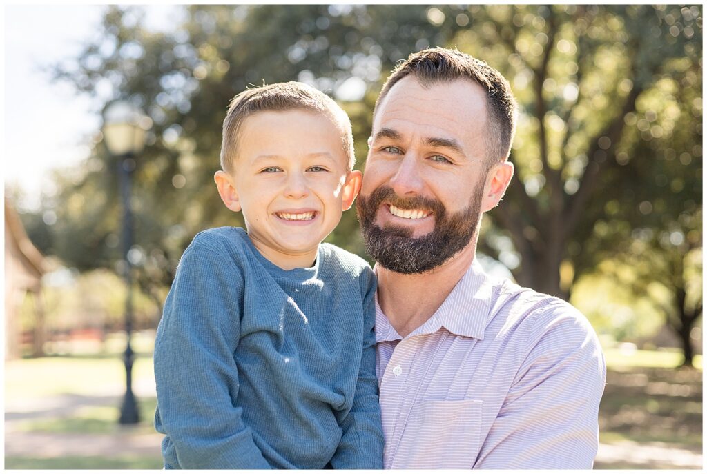 Father holds young son as they smile at the camera of Wisp + Willow Photography during their Texas family session.