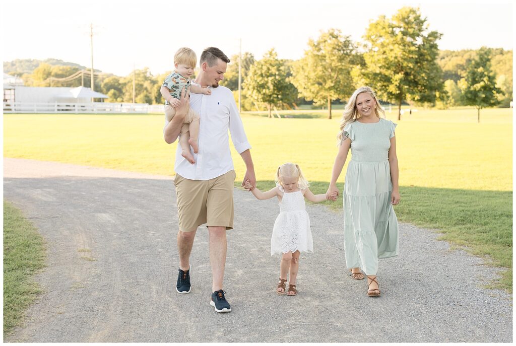 Wisp + Willow Photography Co. capture Harlinsdale Farm portraits for a family of 4 in Franklin, TN.  Dad holds toddler son on his side as both parents hold their daughters hand as they walk the pathway at Harlinsdale Farm.  They coordinate in white and mint colors.  Click to see more live on the blog today!