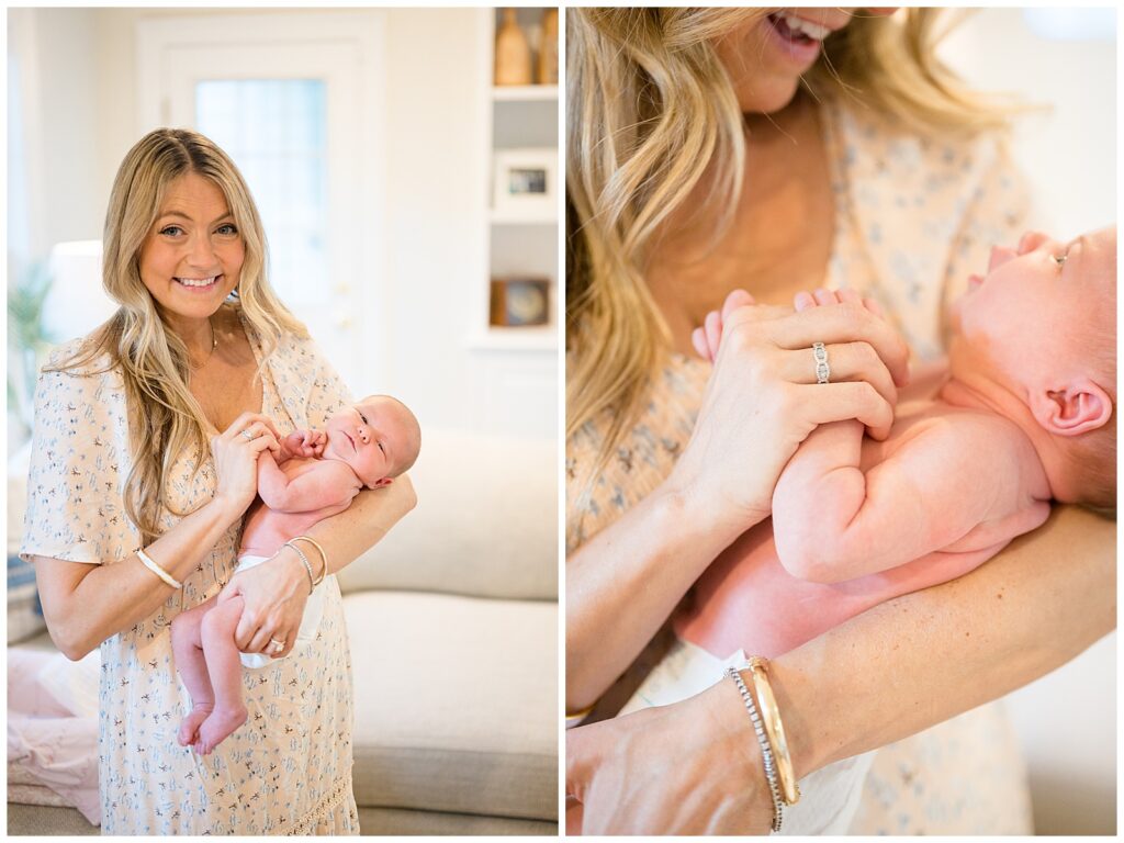 New Mom, wears a cream, short sleeve, long dress with small blue and white flowers on it as she holds her newborn baby girl who is just wearing a diaper.  Their lifestyle newborn session was taken in their home.