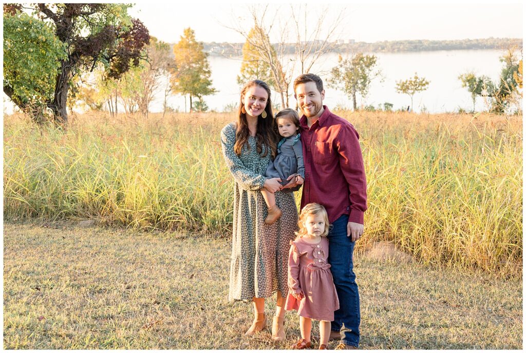 Family of four stand in front of the lake at White Rock Lake in Dallas, TX during their family session with Wisp + Willow Photography Co.  Click to see more on the blog today!