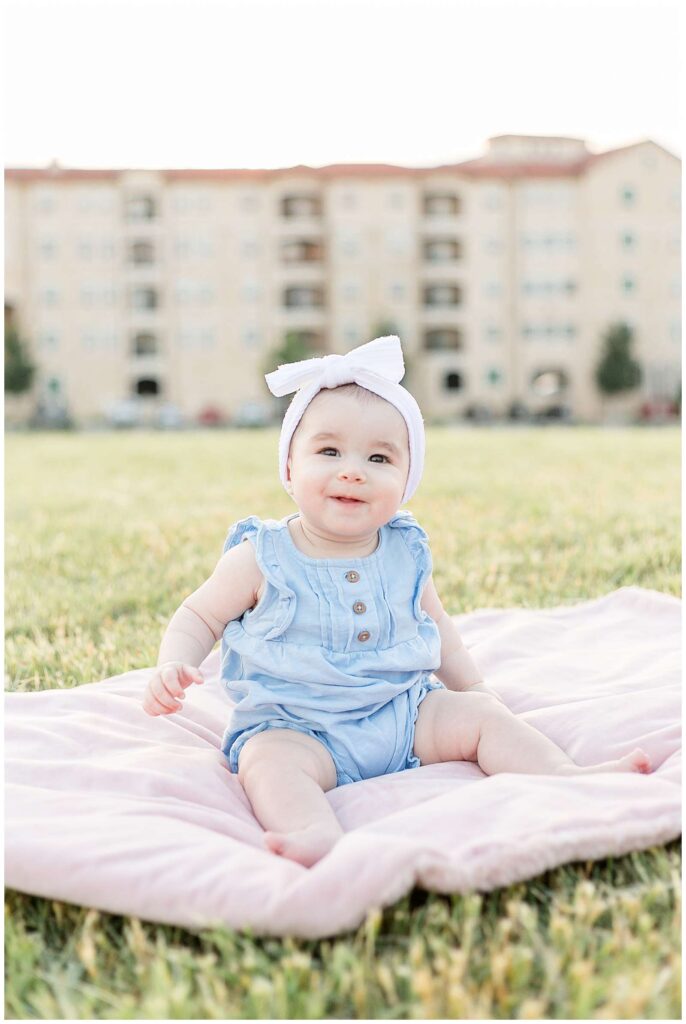 McKinney, TX photographer, Wisp + Willow Photography Co. take a picture of a sweet baby girl who sits up and looks towards the camera wearing a light blue onesie romper!