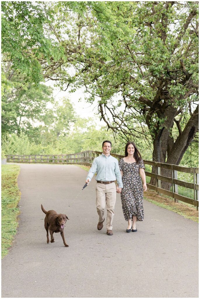 Couple takes a walk with their chocolate lab as they take family portraits at the Shelby Bottom Nature Preserve in Nashville with Wisp + Willow Photography Co.  