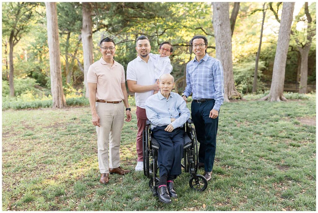 All the boys gather around Grandpa in his wheel cheer and smile at the camera of Wisp + Willow Photography Co. in Dallas, TX for their family portrait session.