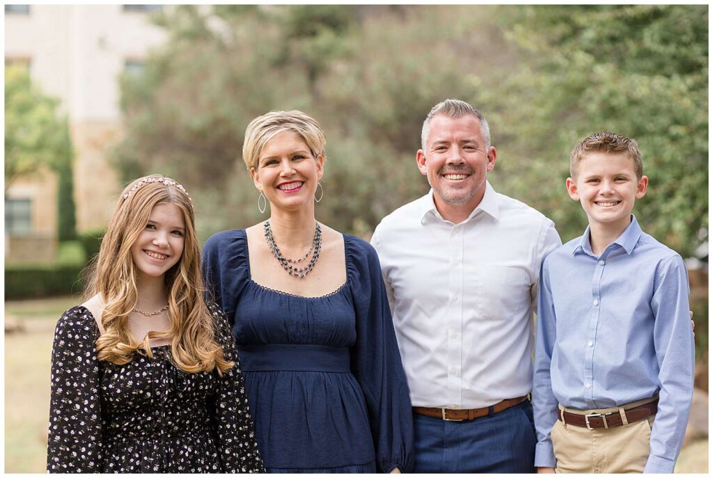 Family of four, with pre-teens, a son and a daughter, stand together at Frisco Central Park for fall mini sessions.