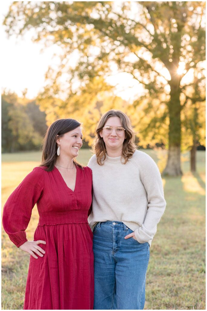 Chattanooga family session with Wisp + Willow Photography Co. show an image of mom standing with her daughter and looking up to her grown daughter.  Her daughter wears a cream colored sweater and glasses and Mom wears a red dress.