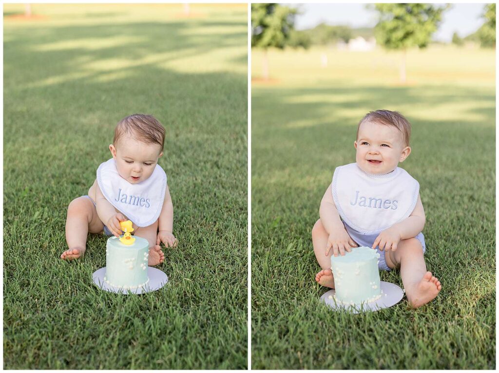 Smash cake session with one year old boy, James, sits on the grass in Franklin, TN with his light blue smash cake in front of him and reaches for the rubber duckies on top and takes them off.  The other image shows him smiling up at his parents with clean hands, face, and toes before he dives in to his smash cake.  He wears a blue diaper cover bottom and a white bib with blue trim that says James on it.