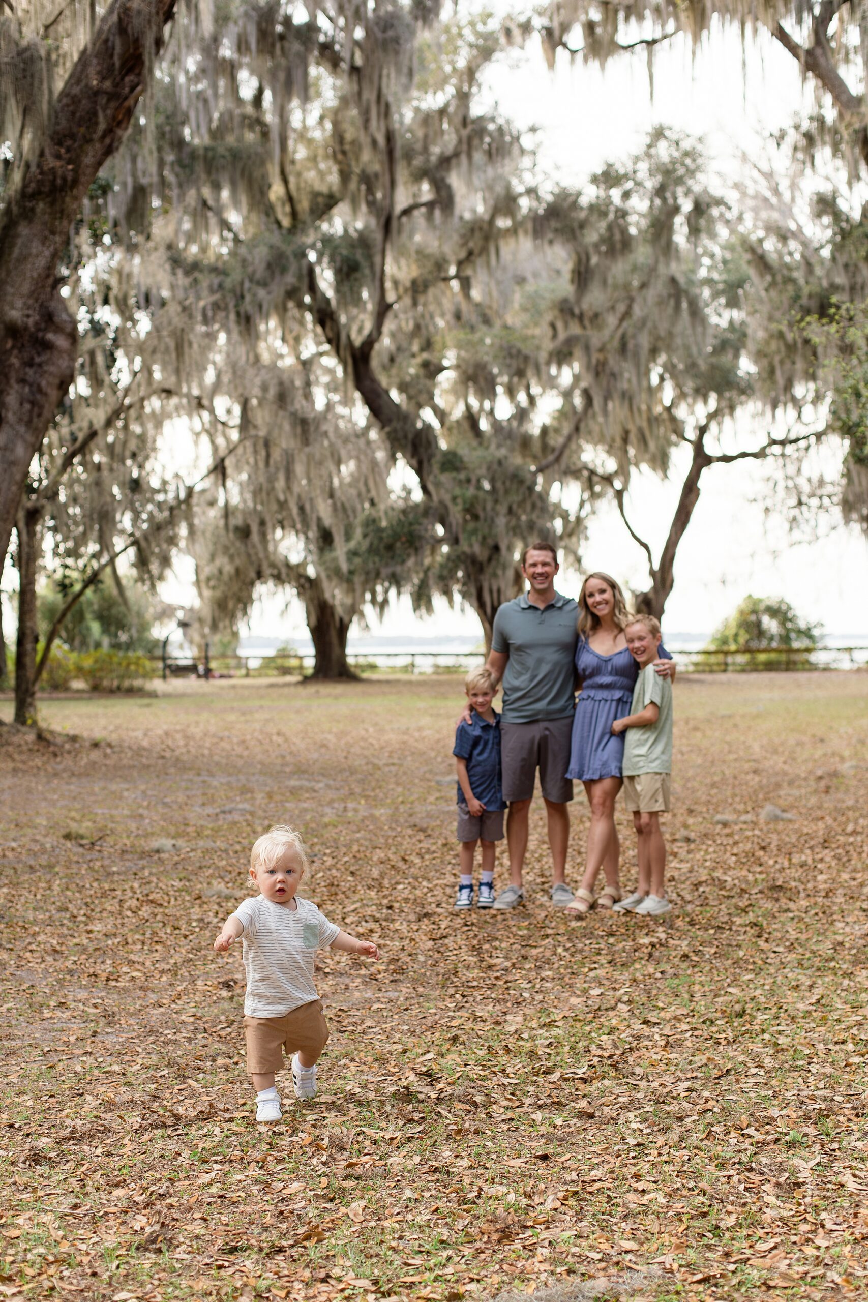Family of 5 poses under spanish moss trees at Alpine Groves Park in Jacksonville, Florida for family session with Wisp + Willow Photography Co. 