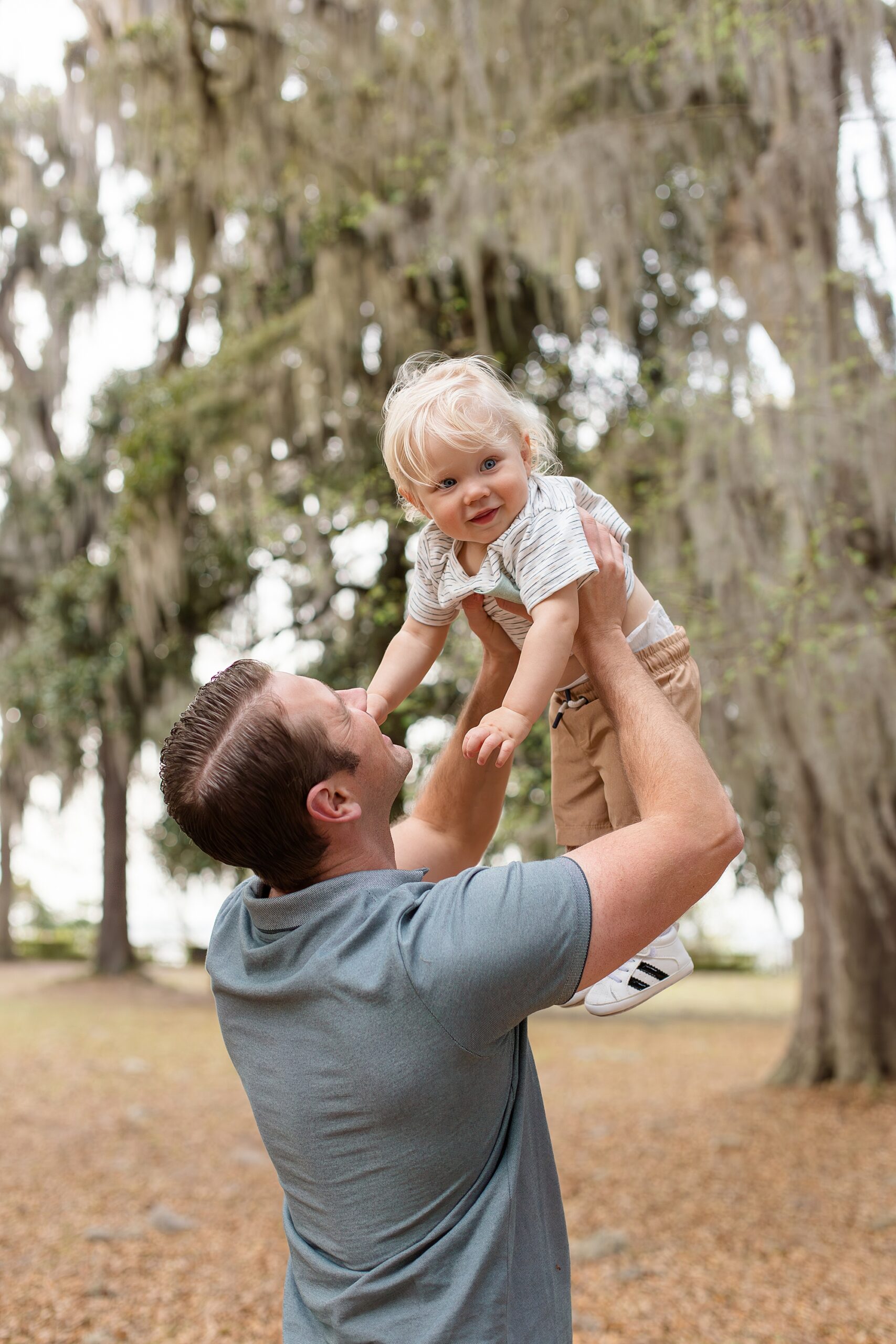Dad holds 1 year old son in the air during Jacksonville family session with Wisp + Willow Photography Co. 